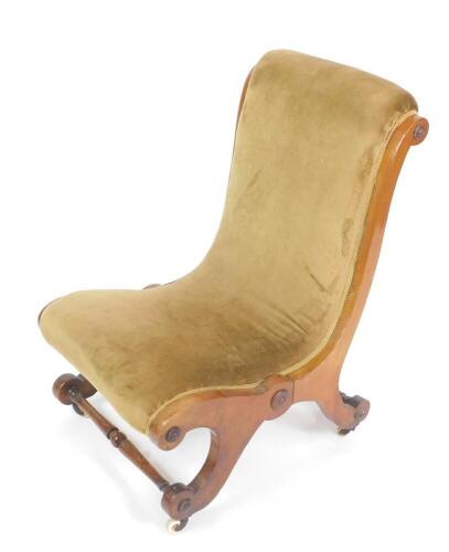 An early Victorian mahogany nursing chair, with scrolling overstuffed upholstery, brass capped on castors.