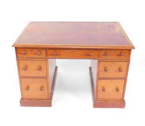 An early 20thC mahogany kneehole desk, with red leather inset top, and three shallow drawers to the frieze and two graduated drawers to the two pedestals, with turned knop handles, on a moulded plinth bases, 74cm H, 75.5cm D, 112cm W.