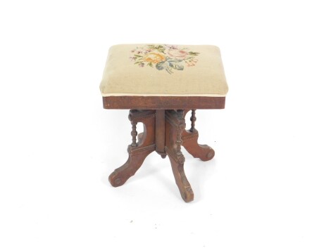 A Victorian oak piano stool, the carved rectangular top with over stuffed tapestry seat decorated with roses, raised on a quatrefoil base.