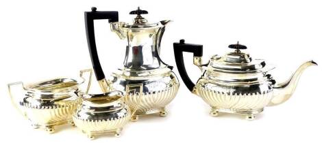 A George V silver four piece tea set, with part fluted body engraved with initials, the coffee pot and teapot with ebonised knop and handle, Sheffield 1923, 69.75 oz gross.