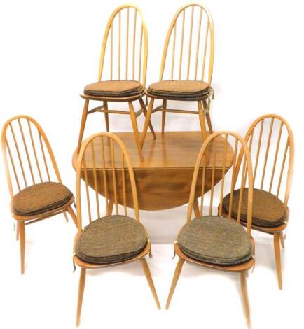 An Ercol elm drop leaf kitchen table, with a circular top on square tapering legs and six matching kitchen chairs, each with an arched back.