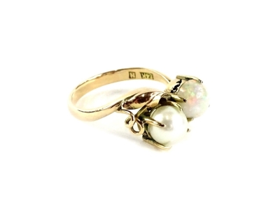 An opal and diamond dress ring, with single opal in four claw setting, and single cultured pearl in four claw setting, on twist design ring head in the form of vines, yellow metal, stamped 14K, ring size O½, 3.5g all in.