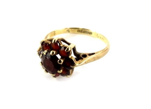 A 9ct gold floral cluster ring, set with garnets, in raised basket design, ring size K, 2g all in, in C H Berry Limited of High Wycombe box.