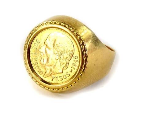 A coin signet ring, set with a single peso dated 1945, on yellow metal band, unmarked, ring size Q, 8.2g all in.