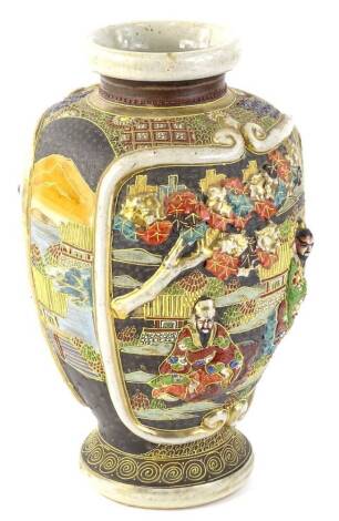 A Japanese earthenware vase, decorated in relief with figures, trees, buildings etc., embellished in tube lining and with gilt borders, signed in red to underside, 31cm H.