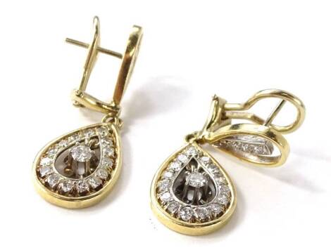 A pair of diamond drop earrings, each consisting of a two colour openwork pear shaped panel, centering with claw set round brilliant cut diamond, surrounded by eight round brilliant cut diamonds, the panel suspends from a second pear shaped two colour ope