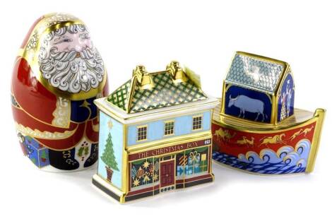 Three Royal Crown Derby Christmas ornaments, a small Noah's Ark toy, a Christmas box or tin and a Father Christmas paperweight with gold button, all boxed.