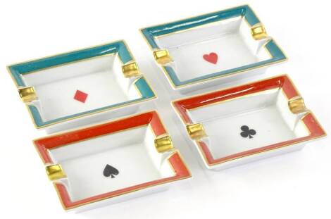 A set of four Limoges porcelain ashtrays, each decorated with suits of cards, within coloured borders in original fitted box.