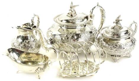 A silver plated three piece tea set, decorated with scrolls, the teapot and sugar bowl with a stylised bird and egg finial, stamped to underside John Turton hand soldered EPBM, a leaf shaped toast rack etc.