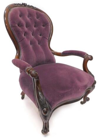 A Victorian mahogany showframe open armchair, the padded button back upholstered in purple fabric, on carved cabriole legs, with ceramic castors.