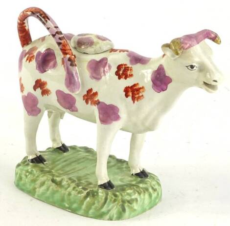 A 19thC lustre glazed Staffordshire cow creamer, on a rectangular green base (AF), 18cm L.