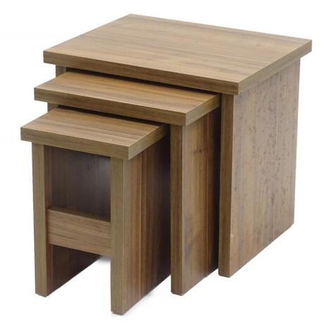 An ex shop display nest of three walnut veneered tables, of plain form on end supports, the largest 50cm W.