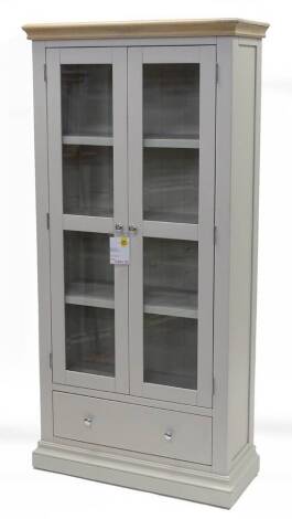 An ex shop display oak and pale grey painted Edinburgh display cabinet, with a limed oak cornice, two glazed doors, and a single drawer on a plinth base, 181cm H, 88cm W.