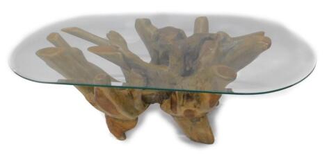 An unusual rustic coffee table, the rectangular glass top with rounded corners and a bevel edge on a carved root base, 126cm W.