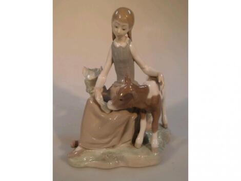 A Lladro figure of a young girl feeding a calf