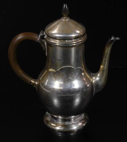 A George V silver coffee pot, with domed lid, wooden handle, beak spout and circular foot, the bellied circular body, marked Goldsmiths, London 1934, the body marked 1936, 22cm H, 14½oz all in.