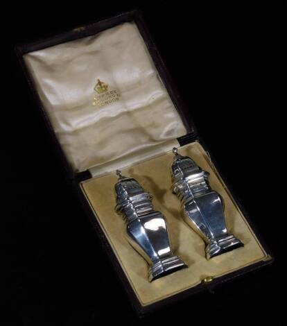 An Edwardian silver pair of pepper pots, with octagonal bodies, domed pierced lids, urn finials and shaped stepped feet, London 1908, 8cm H, 4½oz in Asprey case.