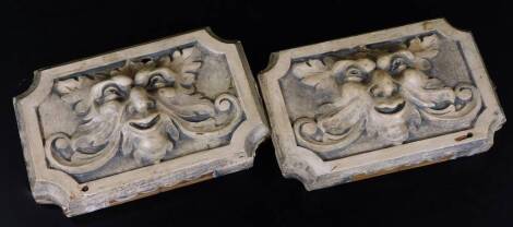 A pair of wooden wall plaques, of inverted rectangular form, raised with figures of The Green Man, in a scroll and leaf outline, probably 19thC, 22cm W. (2)