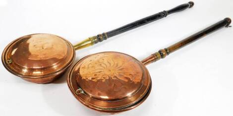 A late 19thC copper warming pan, with turned handle, the main body etched with a sun motif, 88cm H, and a further warming pan. (2)