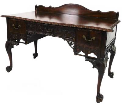 A late 19thC mahogany dressing table, of serpentine form, with gadrooned outline, galleried back and central drawer flanked by two further drawers, with elaborate handles and a blind fret carving beneath, on cabriole legs terminating in ball and claw fee