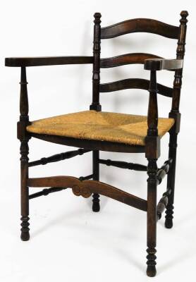 A 19thC country ladder back chair, with rush seat, turned arms, ring turned front legs joined by double side stretchers, with a comb front stretcher, 90cm H.