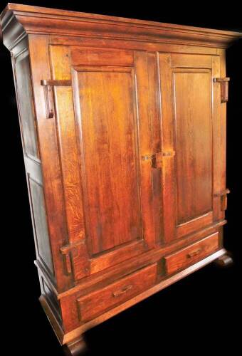 An oak Arts & Crafts style cupboard, with plain fixed cornice raised above two panel doors revealing fitted interior above two drawers beneath, on scroll feet, 183cm H, 155cm W, 50cm D.