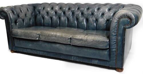 A Victorian style Chesterfield settee, in blue leather, with button back and arms and detachable cushions, on compressed bun feet, 76cm H, 200cm W, 87cm D.