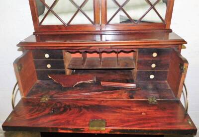 An early 19thC mahogany cabinet bookcase, the fixed moulded dentil top raised above a pair of astragal glazed doors, with adjustable shelves, the sub section set with a secretaire above three long drawers, on splayed feet, 209cm H, 100cm W, 46cm D. - 2