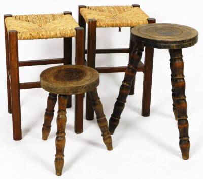 A graduated pair of milking stools, each with circular tops, on triple turned legs, 45cm H, 26cm Dia. and two rush seated stools. (4)