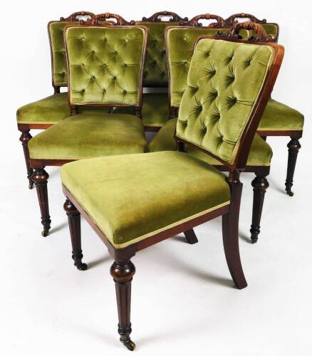A set of six early Victorian mahogany library or dining chairs, each with overstuffed button backs and seats, carved scroll and floral tops and turned front reeded legs terminating in castors, re-uphostered by Peter C Farmer, 94cm H. (6)