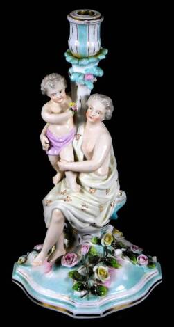 A 20thC continental porcelain candlestick group, formed as a lady semi-clad aside child, on a floral base, polychrome decorated predominately in yellow, turquoise and pink, with gilt highlights, H mark beneath, 34cm H.