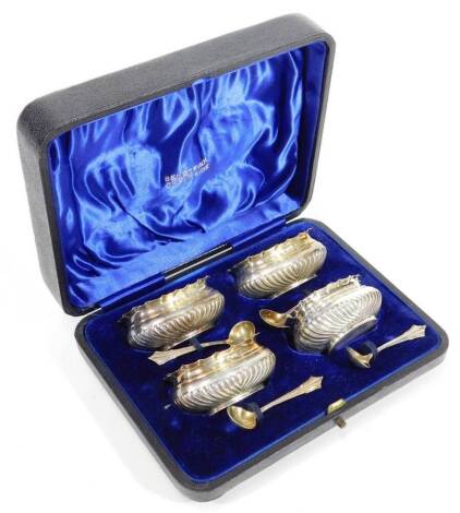 A set of four Victorian silver open salts, each of compressed oval form, partially gadrooned with flared rims and silver gilt interiors, with spoons, Birmingham 1897, 3cm H, 3oz. (cased)