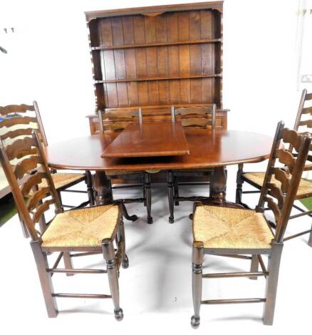 A Stewart & Shacklock oak dining room suite, comprising of D end extending table with one leaf, on twin cabriole pedestals, 76cm H, 212cm W, 107cm D, six (4+2) ladder back with rush style seats and a dresser with Delft racks above three frieze drawers and