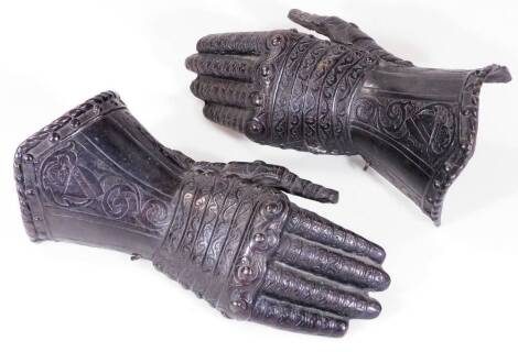 A pair of 19thC style models of gauntlets, chased and repoussé decorated, 30cm W.