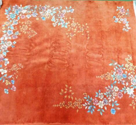 An oriental rug, of large proportion, set with flowers, predominately in blue, green and orange, on an orange ground, with cream border, machine woven, approx. 325cm x 230cm.