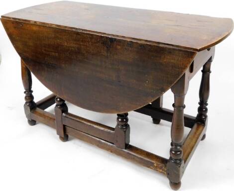 A Jacobean style oak gate leg drop leaf table, with plank top, on turned supports terminating in compressed orb feet joined by block stretchers, when closed 76cm H, 128cm W, 59cm D.
