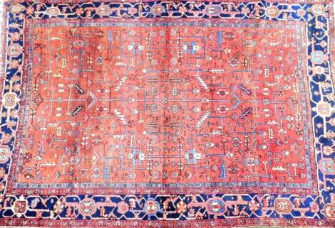 A large Middle Eastern rug, in a floral geometric pattern, predominantly in red and blue, approx. 317cm x 266cm.