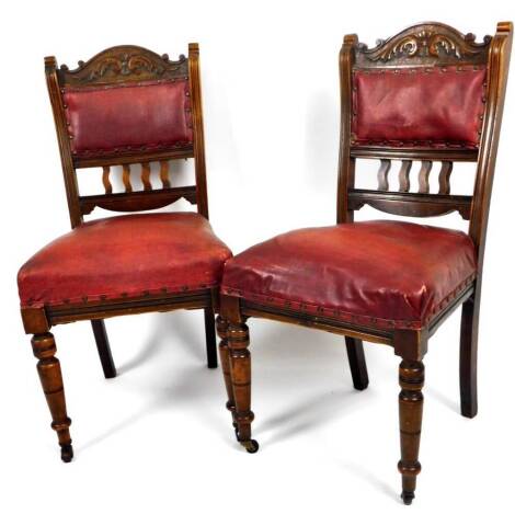 A pair of late 19thC walnut dining chairs, each with curved cresting rails carved with scrolls, above a studded leather back and overstuffed seat, on turned front tapering legs terminating in castors, 92cm H. (2)