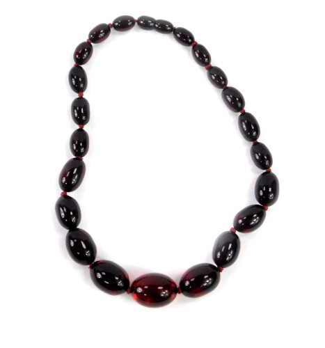 A string of graduated cherry amber beads, twenty three beads, largest 24mm W, 48.2g.