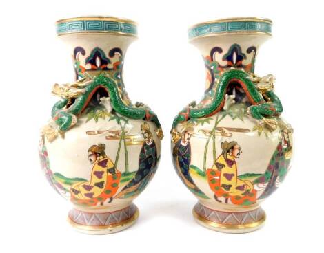 A pair of early 20thC Japanese earthenware vases, of baluster form, moulded with dragons, decorated in enamels with figures, gilt heightened, four character mark, 31cm H.