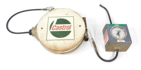 A Castrol wall mounted oil dispenser, with circular dial for litres dispensed, with extendable hose in white painted metal holder, and red and green Castrol decals.