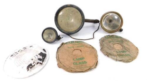 A brass Lucas headlamp, further Lucas headlamp with mounting cover, side light, two Lucas headlamp glasses and one other. (6)