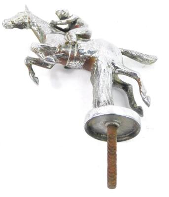 A chrome car mascot modelled as a jockey and racehorse, jumping a fence.