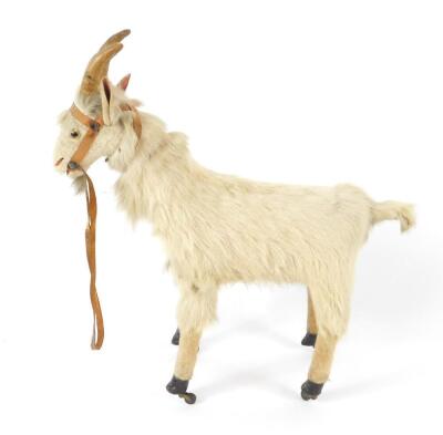 A late 19thC pull-a-long goat, possibly Sonnenberg, with a composition head and body, brown glass eyes and leather straps, raised on four brass castors, the head moves to produce a goat's sound, 43cm W.