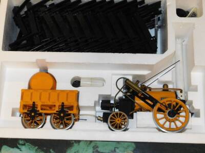 A Hornby 3 1/2" gauge model of Stephenson's Rocket, boxed, together with three coaches, with opening doors and detailed interior, G104, and various track, G102, all boxed. (5) - 2