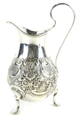 A Victorian silver baluster shaped cream jug, embossed with scrolls, flowers, etc., surrounding a vacant cartouche, on three scroll cast feet, Birmingham 1878, 3¾oz.