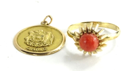 Two items of modern jewellery, comprising a coral set dress ring, in yellow metal setting, unmarked, ring size P, and a Chile pendant, marked to rear Rdo a Abuolita Flora las mietos, yellow metal, stamped 18k, the pendant 2.1g. (2)