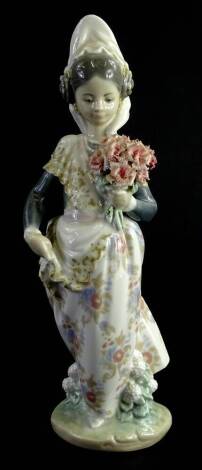 A Lladro figure of a girl wearing veil, holding bouquet of flowers, polychrome decorated, printed marks beneath, 23cm H.