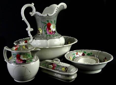 A late Victorian wash set, comprising jug and bowl, further bowl and toothbrush holder, 19cm W, decorated with flowers, on a white ground.