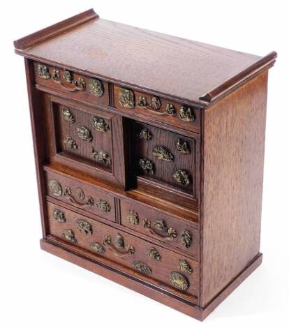 A Japanese shodhana table cabinet, with drawers and sliding panels, decorated with applied embellishments including a toad, crab, fish and figures, 33cm H.